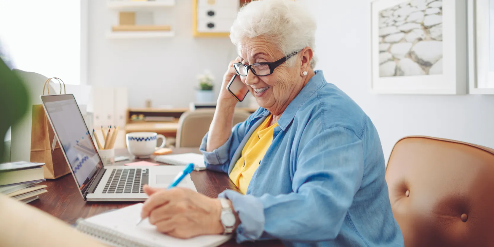 Seniors Stay Safe Against Online Scams - A woman talking on the phone and writing down notes