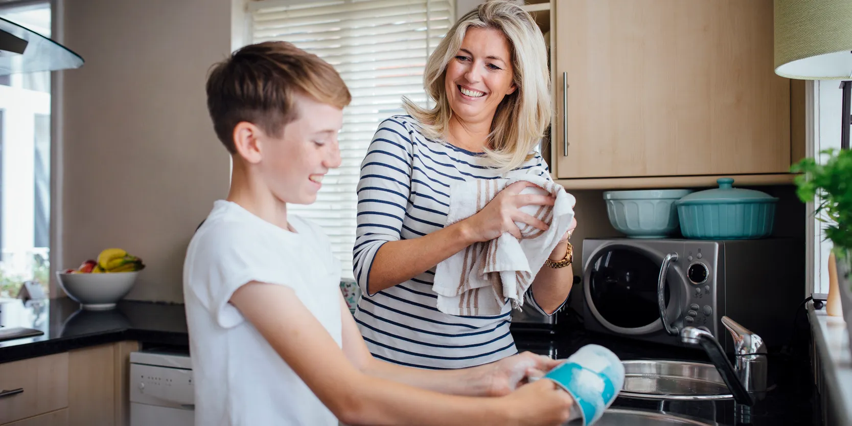 Traditional Allowance vs. Debit Card - Mother and son washing dishes