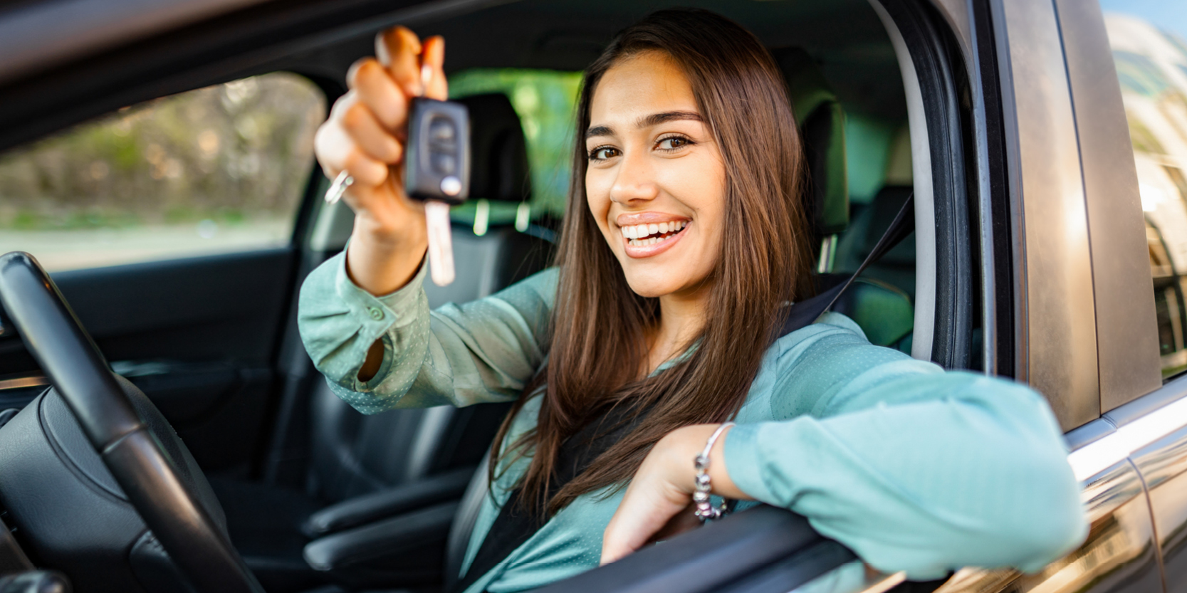 Woman sitting in a car, holding her car key up to the camera