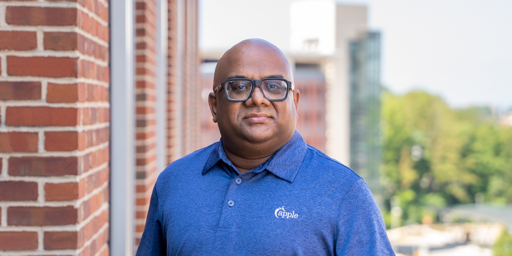 From the Core - photo of Anwar outside in a blue shirt with the Apple FCU logo on it
