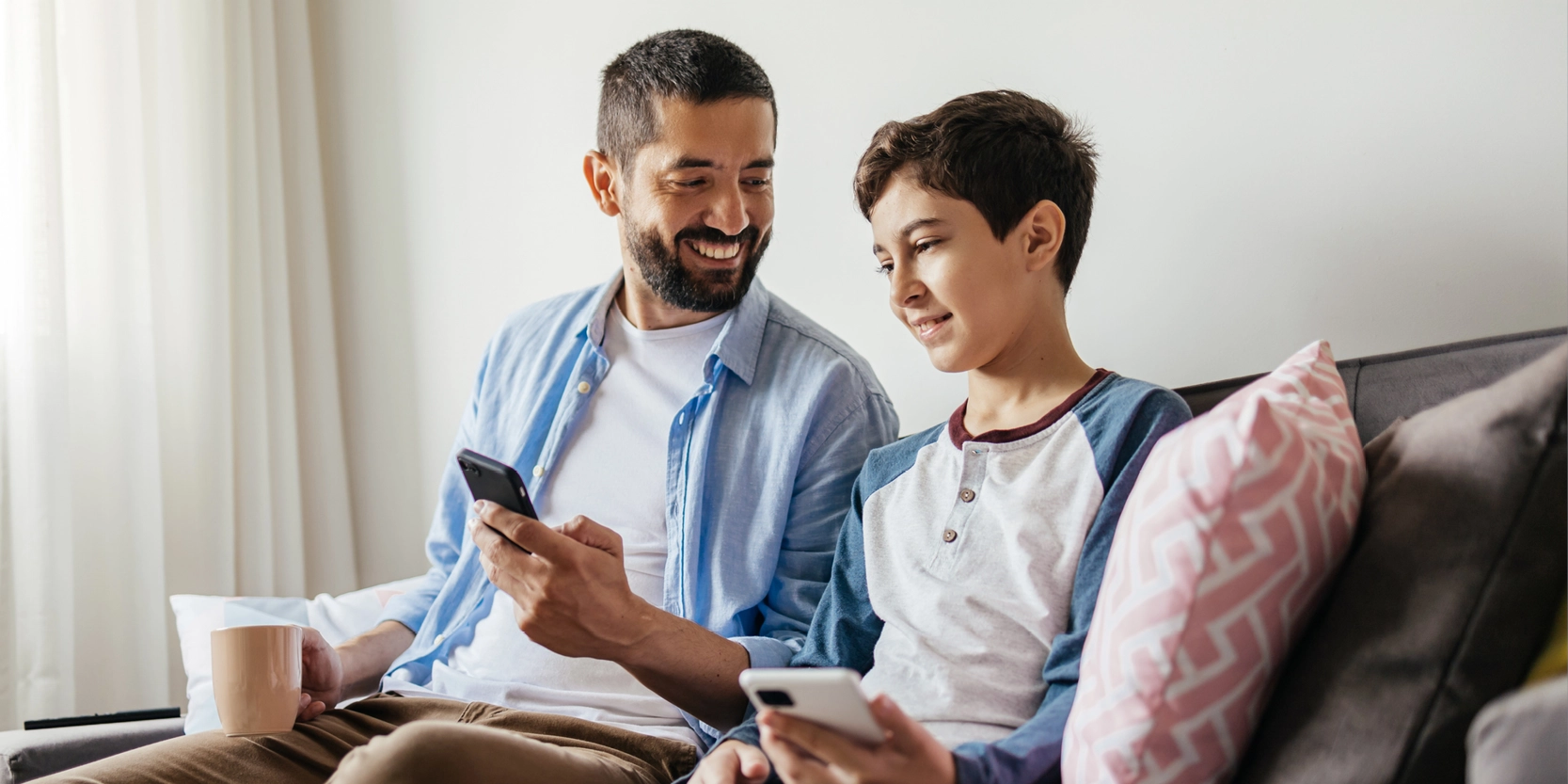 Protect Against Child Identity Theft - Father and son looking at phone on couch